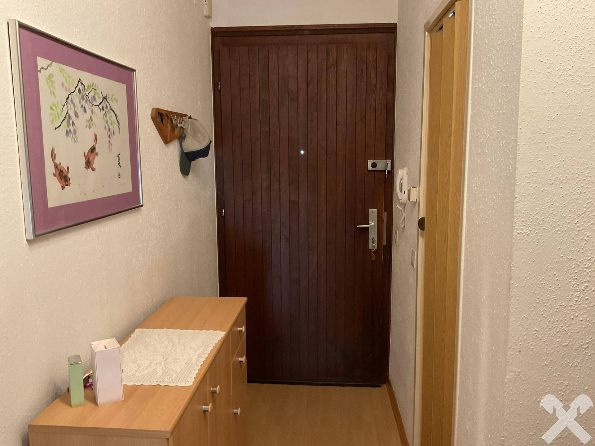 Eingangsbereich mit Holztür, Parkettboden und einer Kommode, die einen freundlichen Empfang bietet.