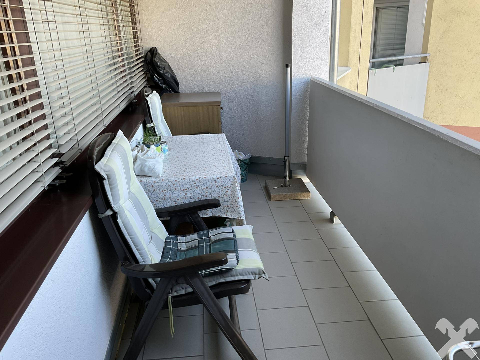 Schmaler Balkon mit Fliesenboden und einfacher Bestuhlung, bietet Platz für eine kleine Sitzecke.