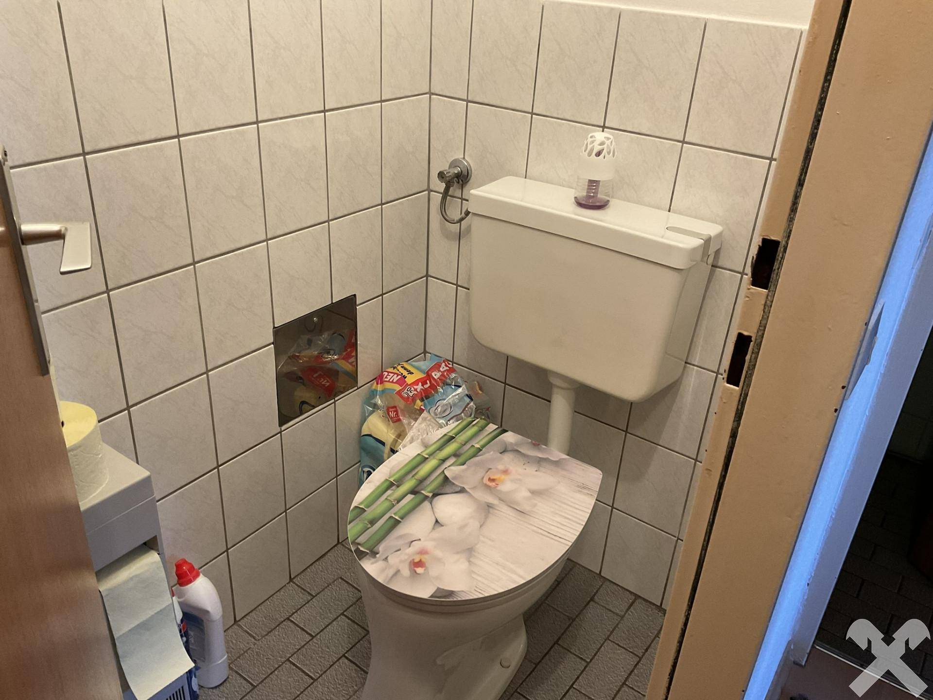 Separate Toilette mit Fliesen an Wänden und Boden, ausgestattet mit einem Standard-WC.