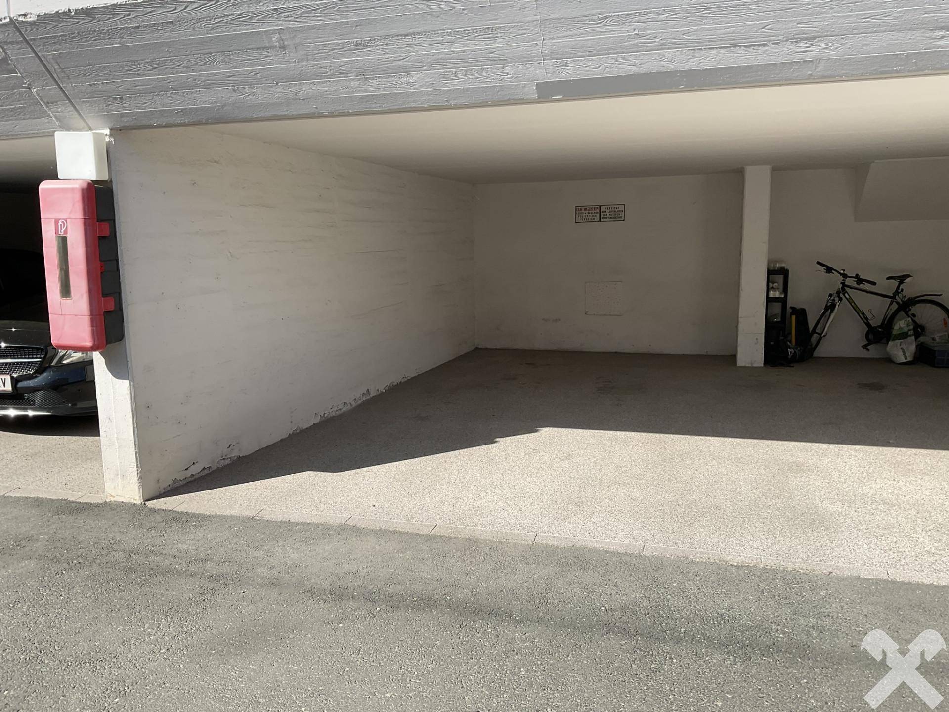 Überdachter Stellplatz in einer Tiefgarage, bietet sicheren Parkraum für Fahrzeuge und Fahrräder.