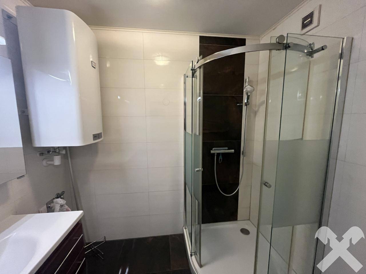 Modernes Badezimmer mit Duschkabine, weißen Fliesen und Warmwasserboiler.