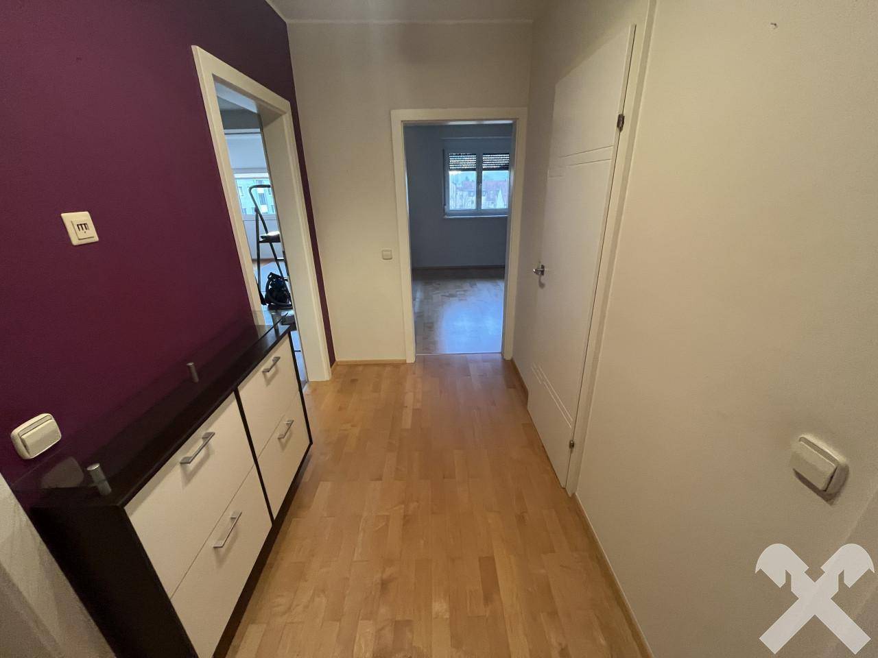 Flur mit Parkettboden, Schuhschrank und Zugang zu weiteren Zimmern.