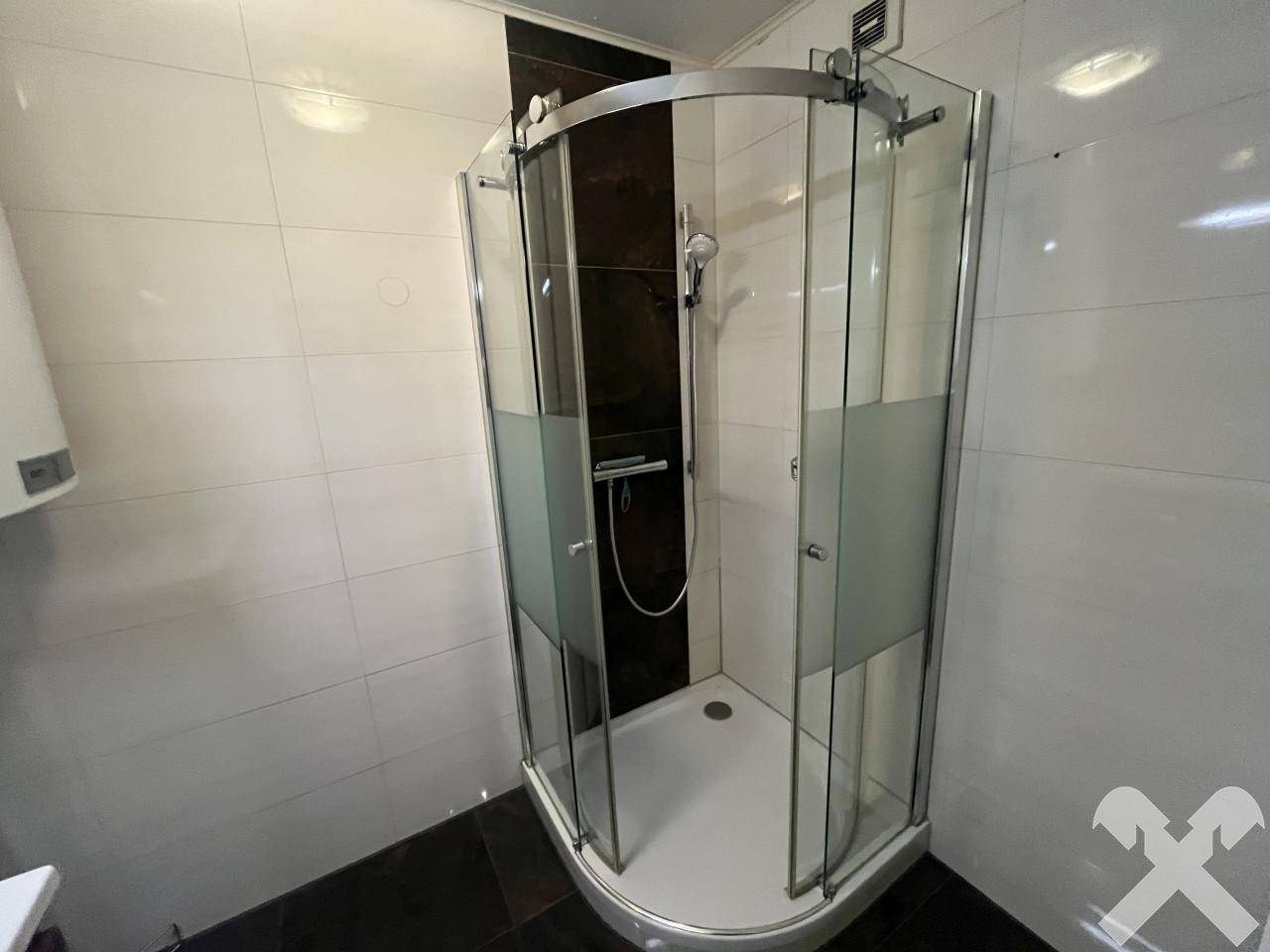 Helles Badezimmer mit Eckduschkabine und weißen Wandfliesen.
