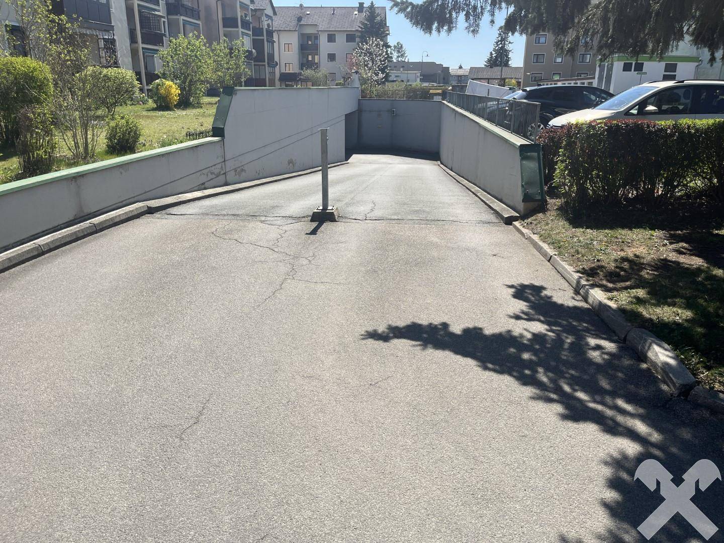 Zufahrt zur Tiefgarage mit Rampe und Schranke.