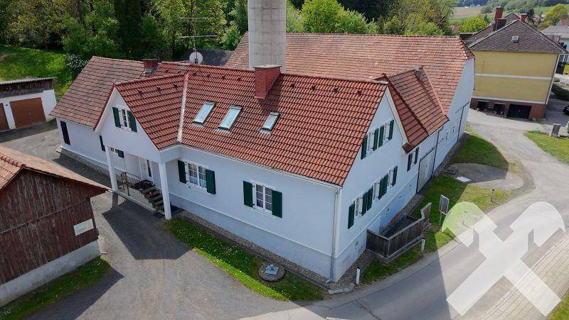 Ansicht eines Gebäudeteils mit roten Ziegeldächern, grünen Fensterläden und Dachfenstern.