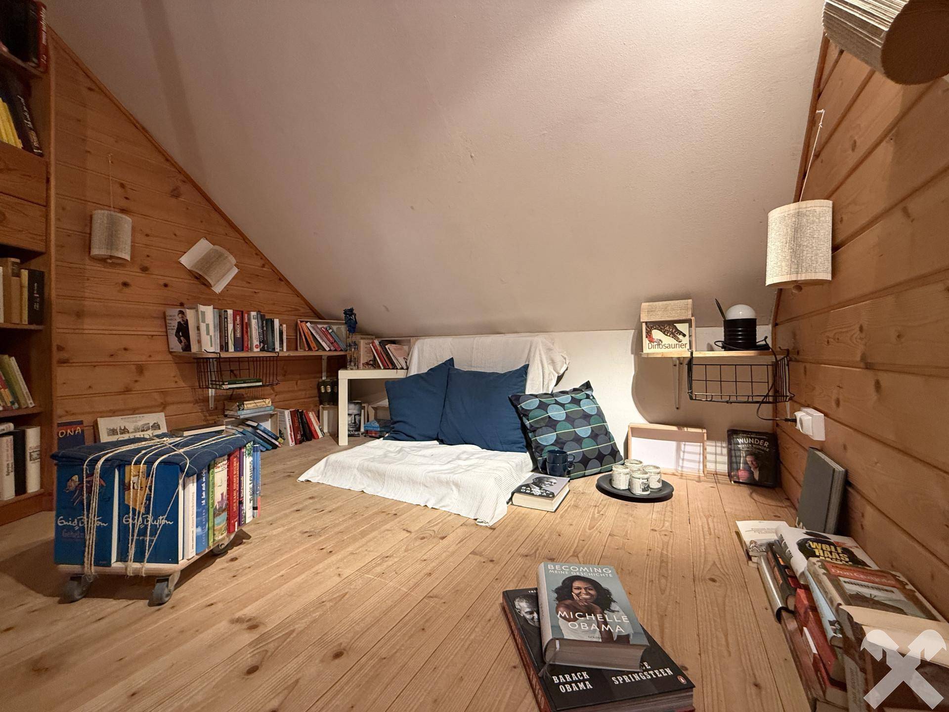 Leseecke im Dachgeschoss mit vielen Büchern, Holzboden und schräger Decke.