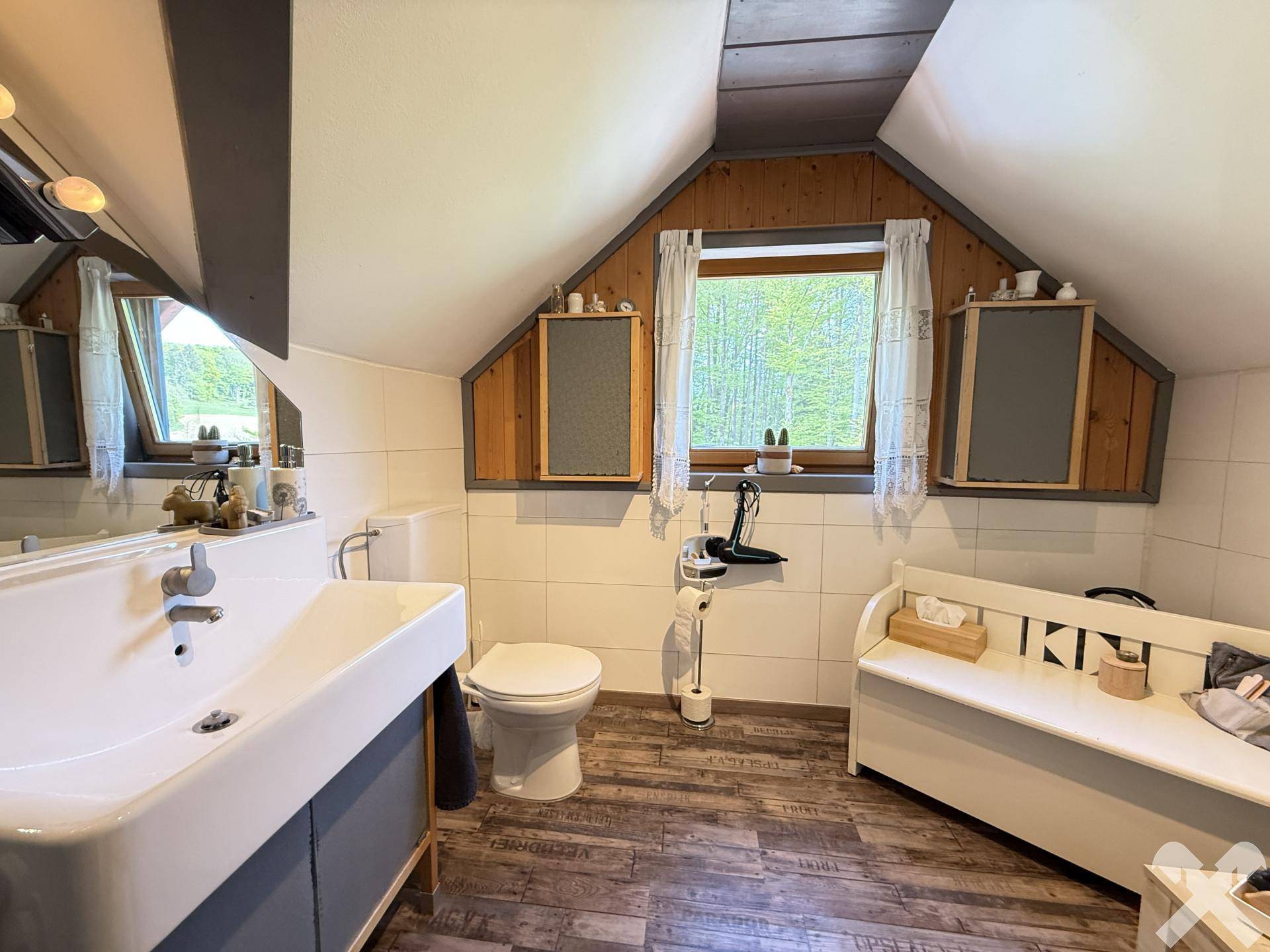 Badezimmer im Dachgeschoss mit Waschtisch, WC, Fenster und schräger Decke.