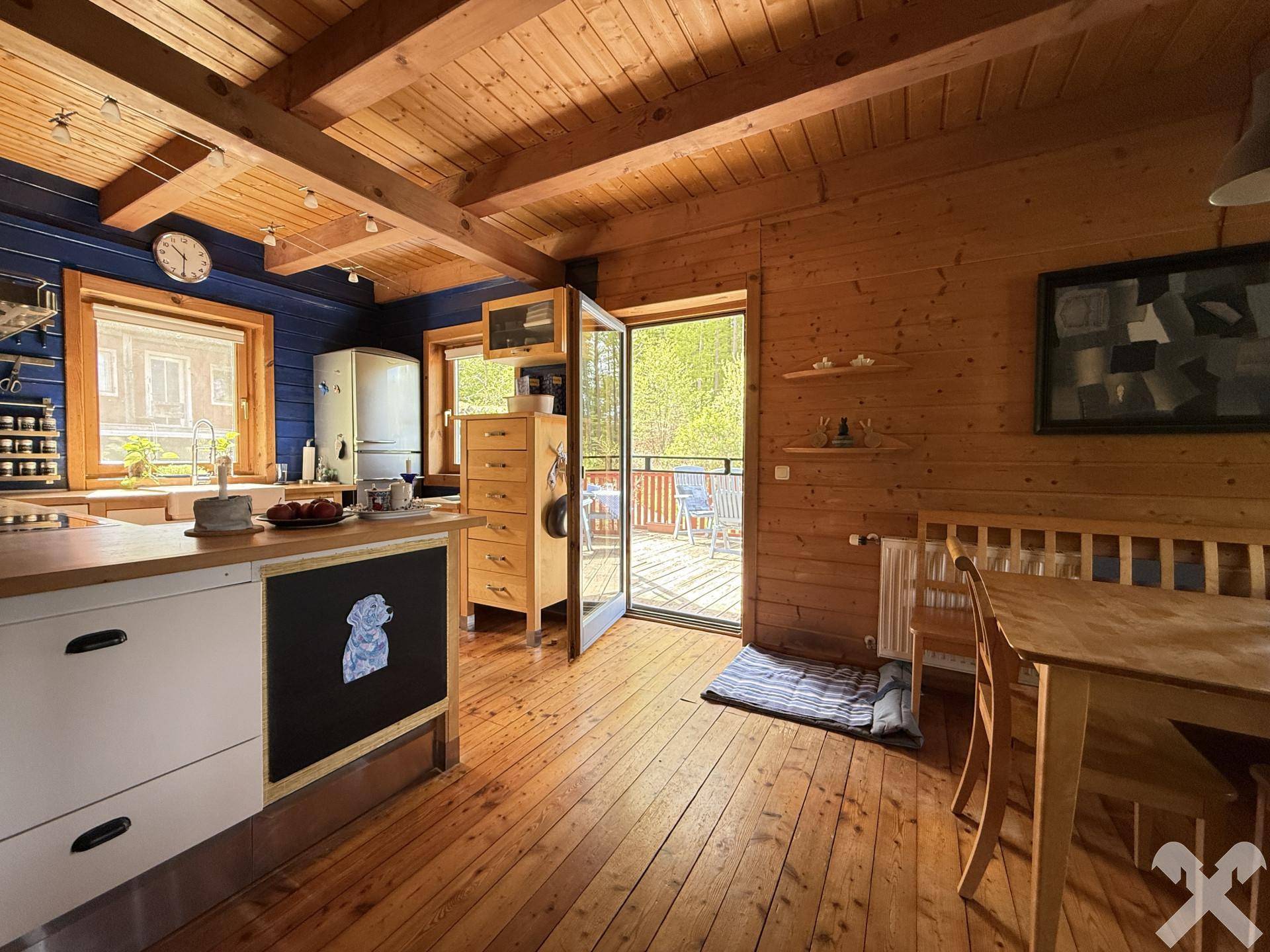 Helle Küche mit Holzbalkendecke, Holzboden und Zugang zur Außenterrasse.