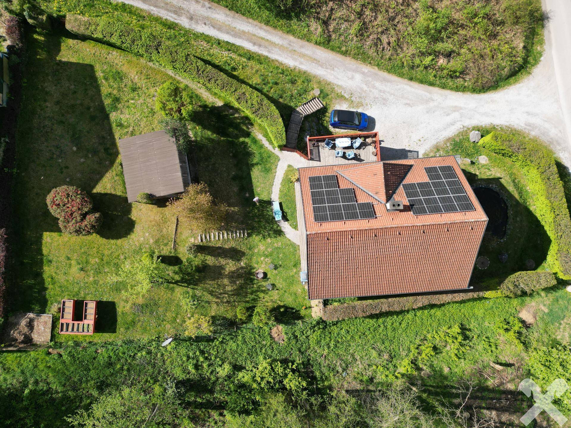Draufsicht auf das Anwesen mit Haus, Photovoltaikanlage, Garten und Zufahrt.