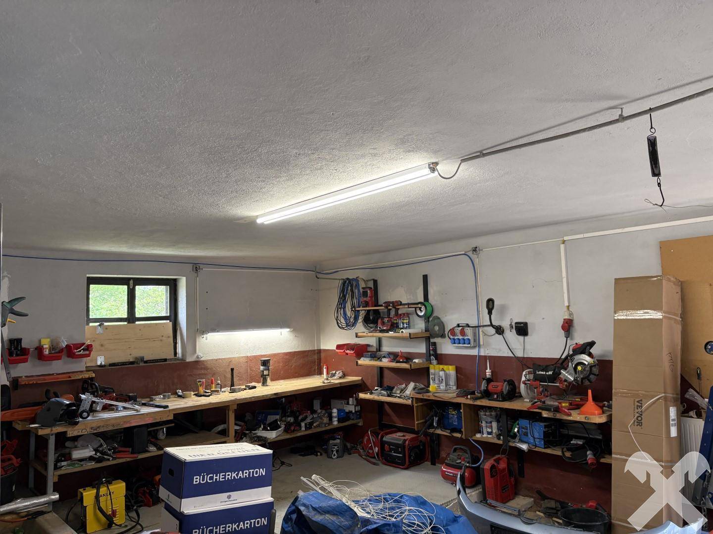Werkstatt mit Arbeitsbänken, Werkzeugen und guter Beleuchtung, ideal für handwerkliche Tätigkeiten.