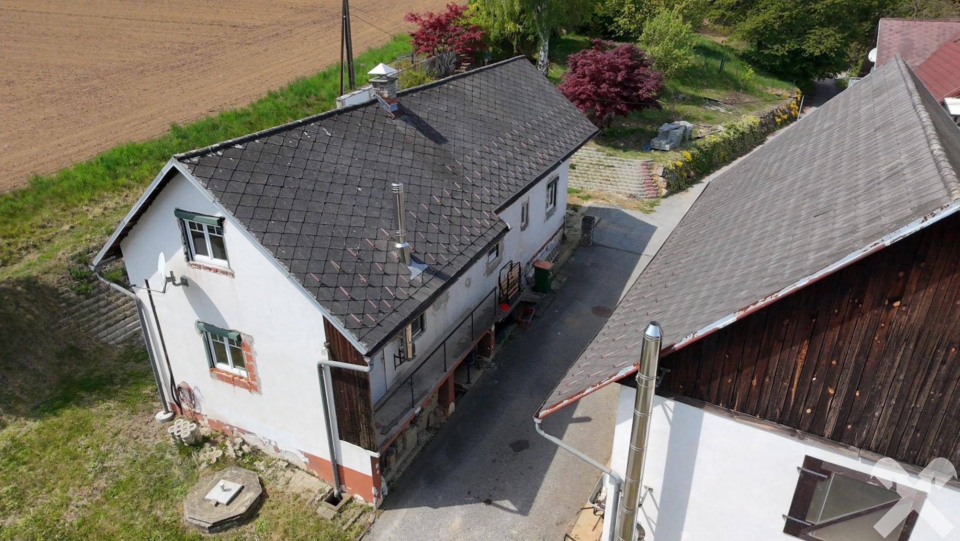 Luftaufnahme des Anwesens mit Haupt- und Nebengebäude, umgeben von Grünflächen.