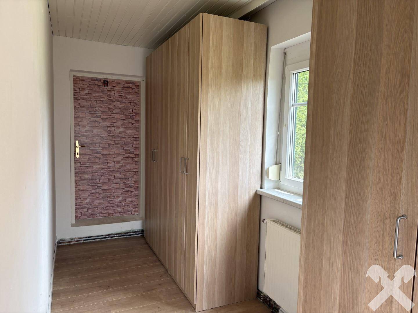 Flur mit geräumigen Holzschränken und einem Fenster, das Tageslicht hereinlässt.
