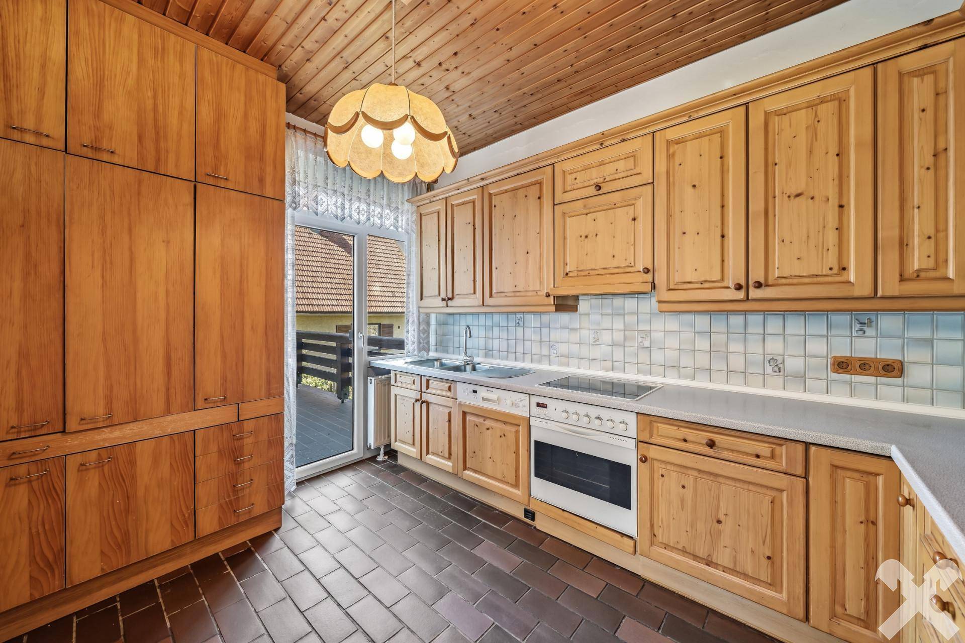 Traditionelle Holzküche mit Einbauschränken, Fliesenboden und Zugang zum Balkon.