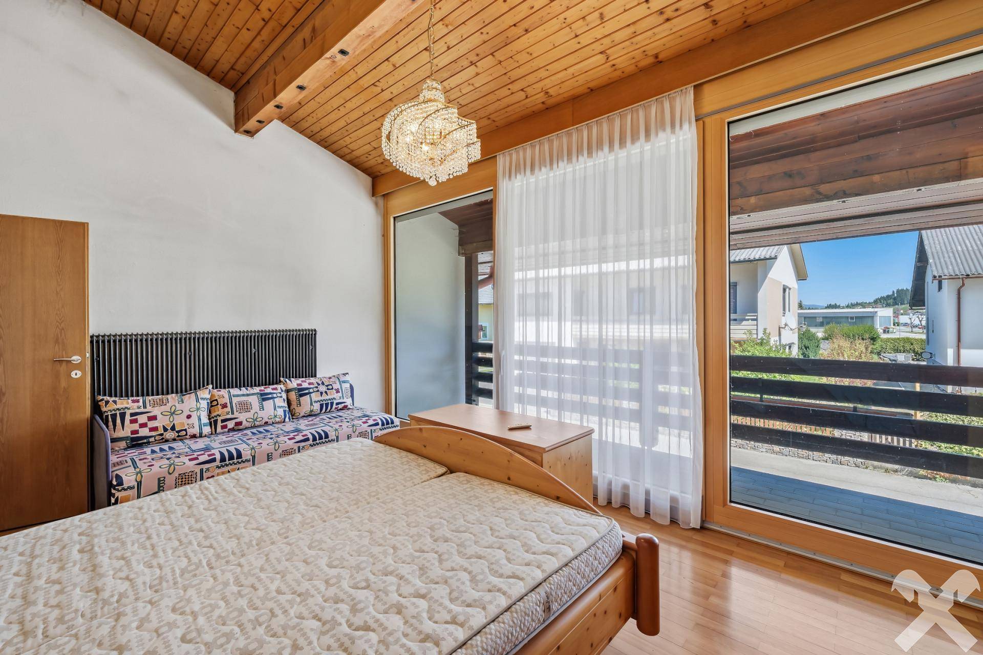 Schlafzimmer mit Holzboden, hohen Decken und großen Fenstern mit Balkonzugang.
