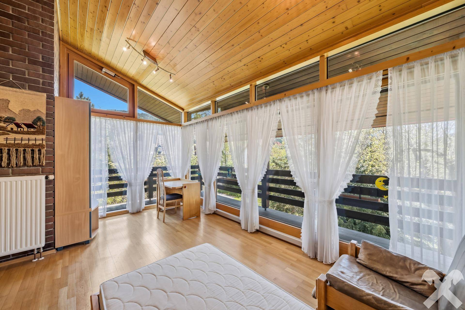 Helles Zimmer mit Holzboden, großen Fensterfronten und weitem Ausblick.