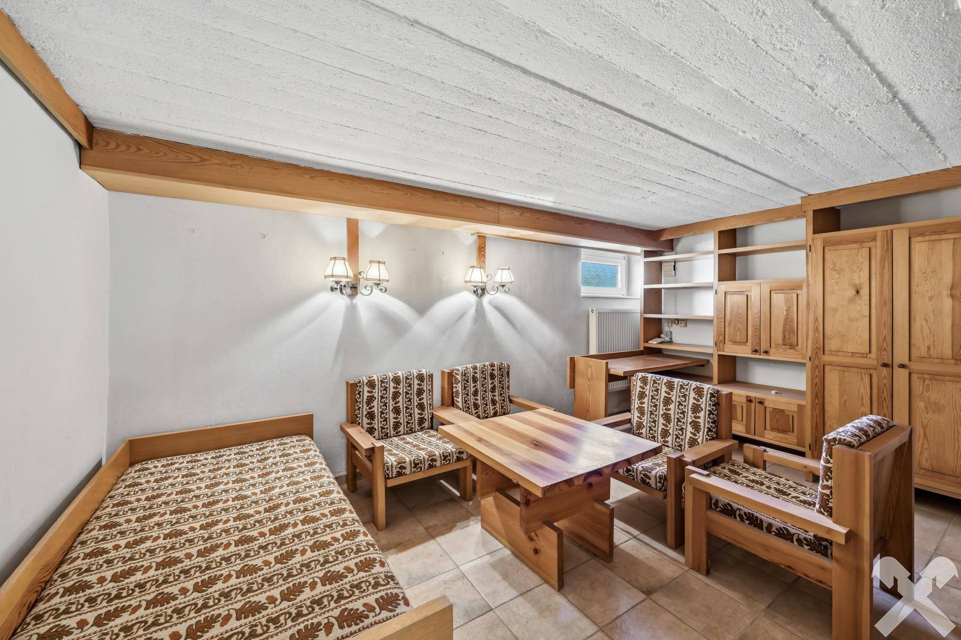 Gemütliches Schlafzimmer im Untergeschoss mit Holzmöbeln und Fliesenboden.