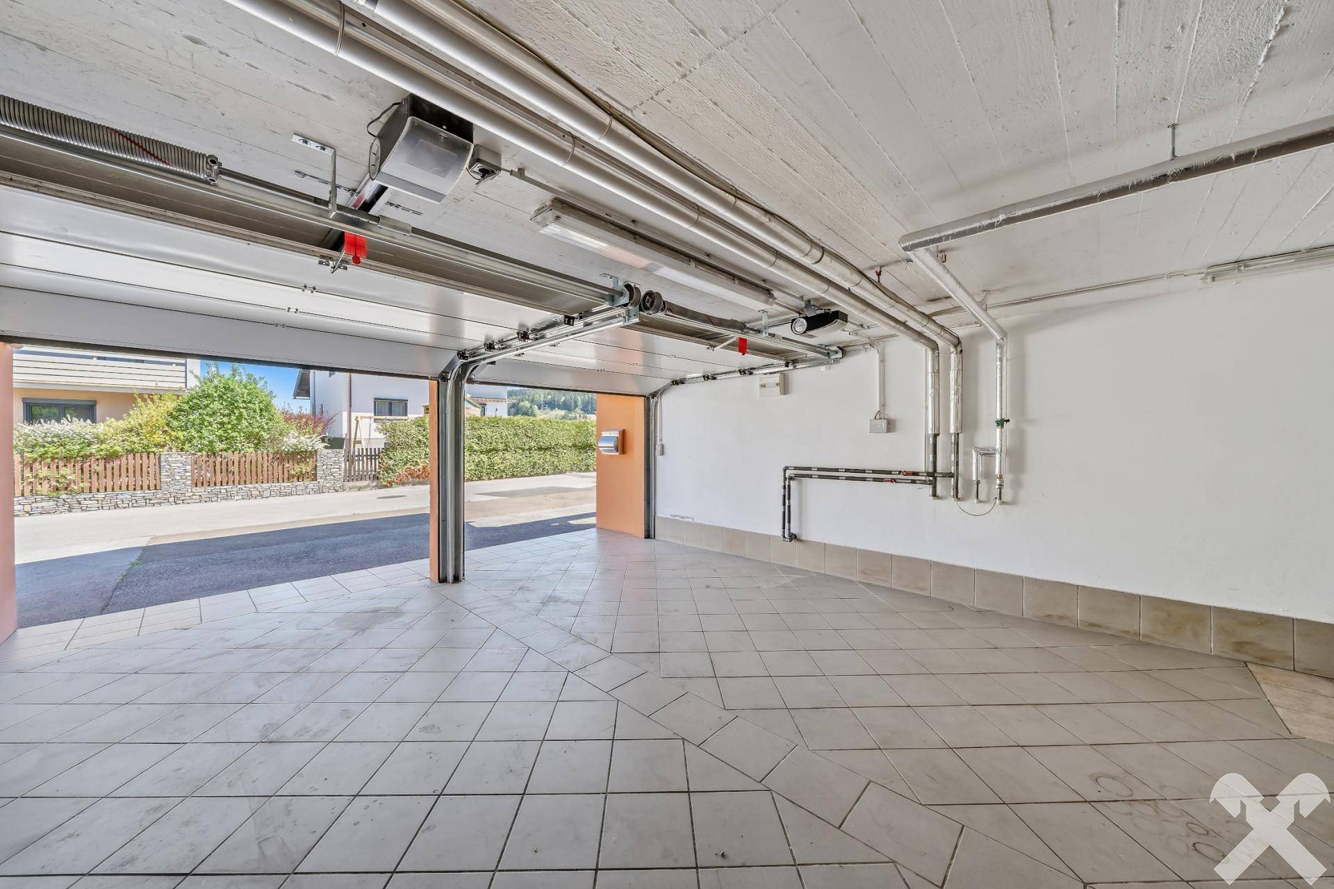 Geräumige Garage mit Fliesenboden und automatischem Garagentor.