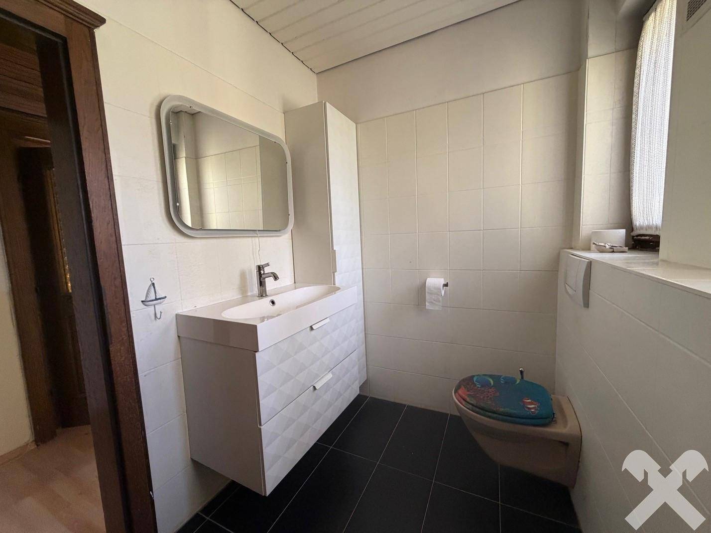 Modernes Badezimmer mit stilvollem Waschtisch, Toilette und weißen Fliesen an den Wänden.
