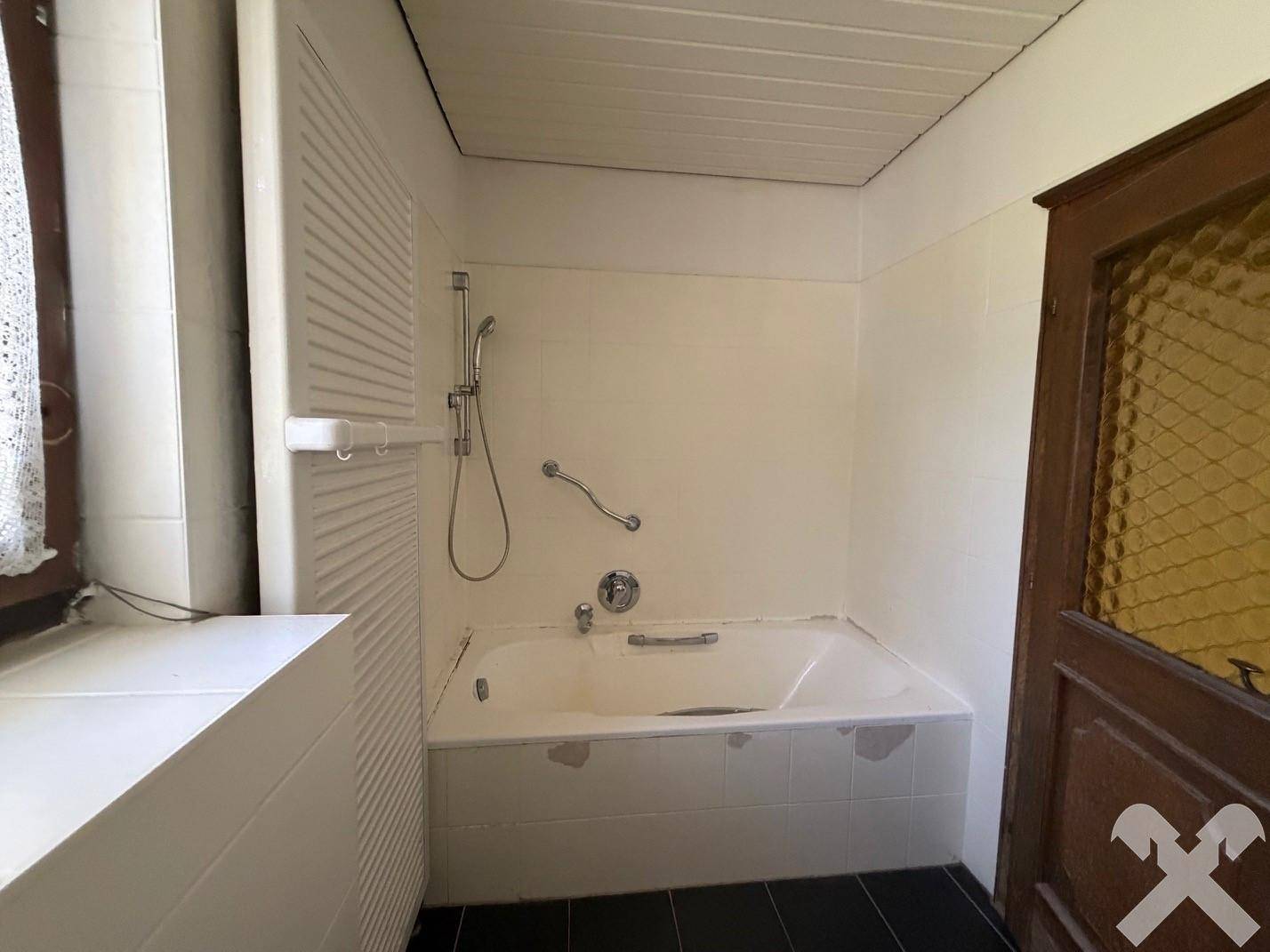Badezimmer mit Badewanne, Duschvorrichtung und Haltegriffen für zusätzliche Sicherheit.