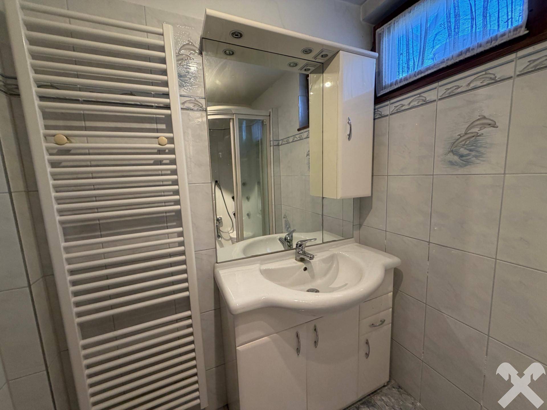 Funktionales Badezimmer mit Waschbecken, Spiegel und beheiztem Handtuchhalter.