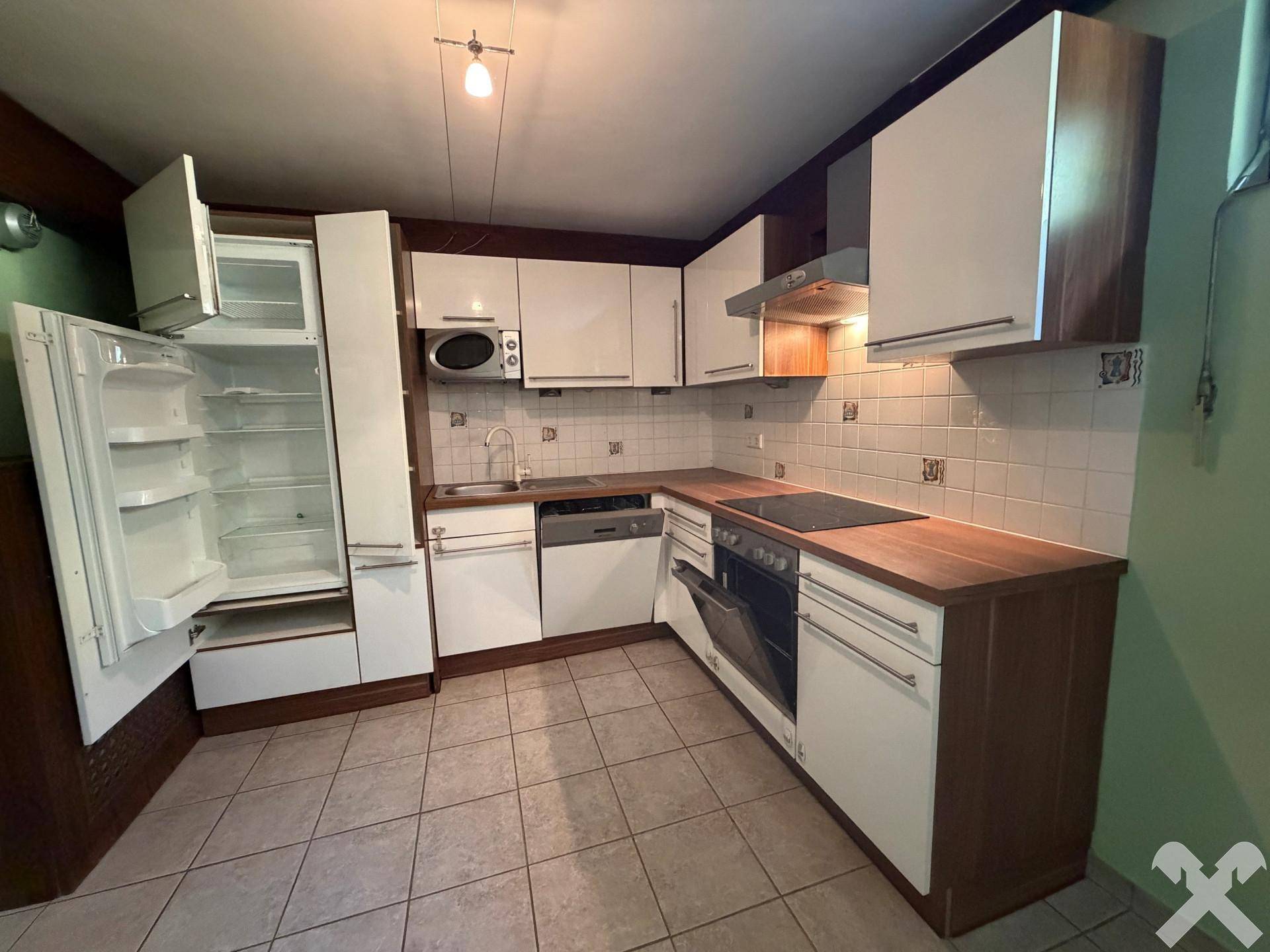 Voll ausgestattete Küche mit weißen Schränken, Kühlschrank und Mikrowelle.