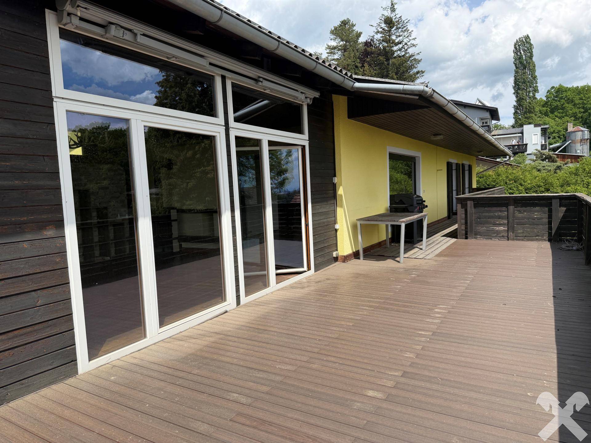 Große Glasfronten vom Terrassenbereich aus gesehen, die den Innenraum mit Licht durchfluten.