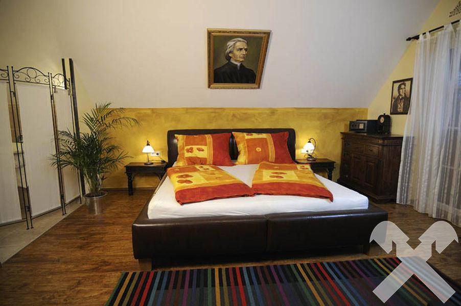 Geräumiges Schlafzimmer mit Doppelbett, Holzboden und Dachschräge, hell und einladend.