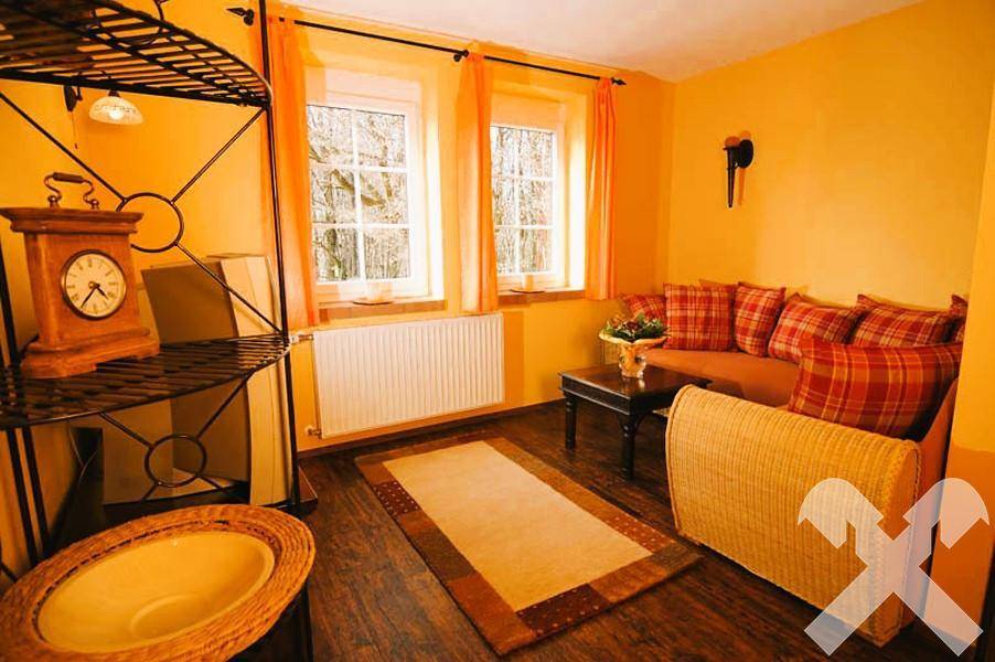 Gemütliche Sitzecke mit Sofa, Holzboden und zwei Fenstern, ideal als Gästezimmer.
