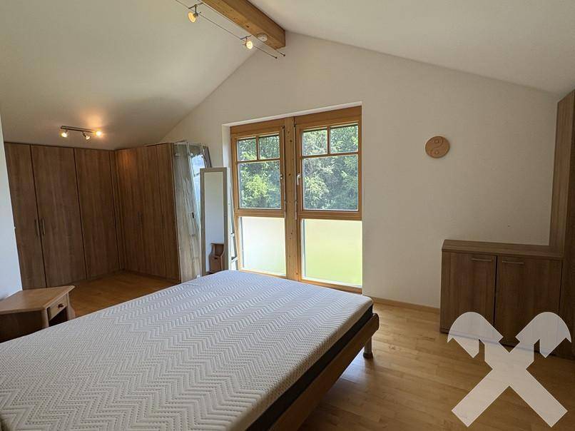 Schlafzimmer im Dachgeschoss mit Holzboden, großen Fenstern und Einbauschränken.