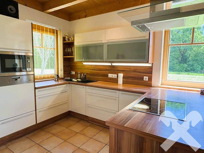 Helle Einbauküche mit Holzdetails, modernen Geräten und viel Stauraum, mit Fensterblick.