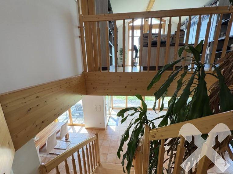 Holztreppe führt vom Erdgeschoss in die obere Etage, mit Blick auf den offenen Wohnbereich.