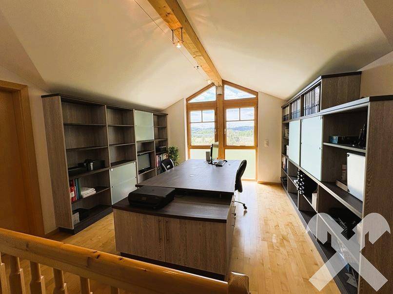 Geräumiges Büro im Dachgeschoss mit Holzboden, großen Fenstern und viel Stauraum.