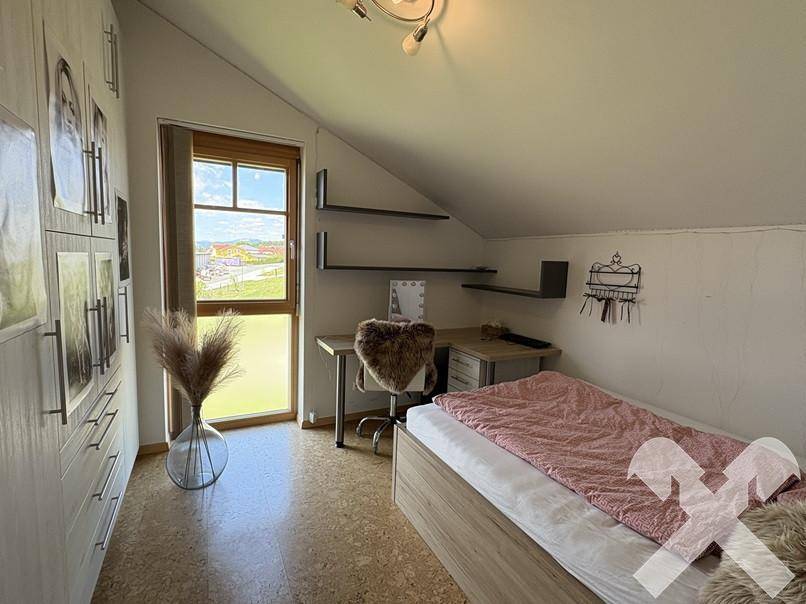 Kinderzimmer mit Korkboden, Einzelbett und Fenster mit Blick nach draußen.