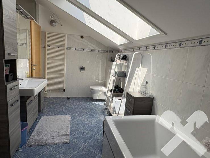 Geräumiges Badezimmer im Dachgeschoss mit Badewanne, WC, Waschbecken und Dachfenstern.