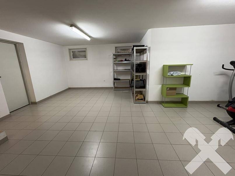 Großer Kellerraum mit Fliesenboden und Regalen, bietet viel Stauraum und Nutzungsmöglichkeiten.