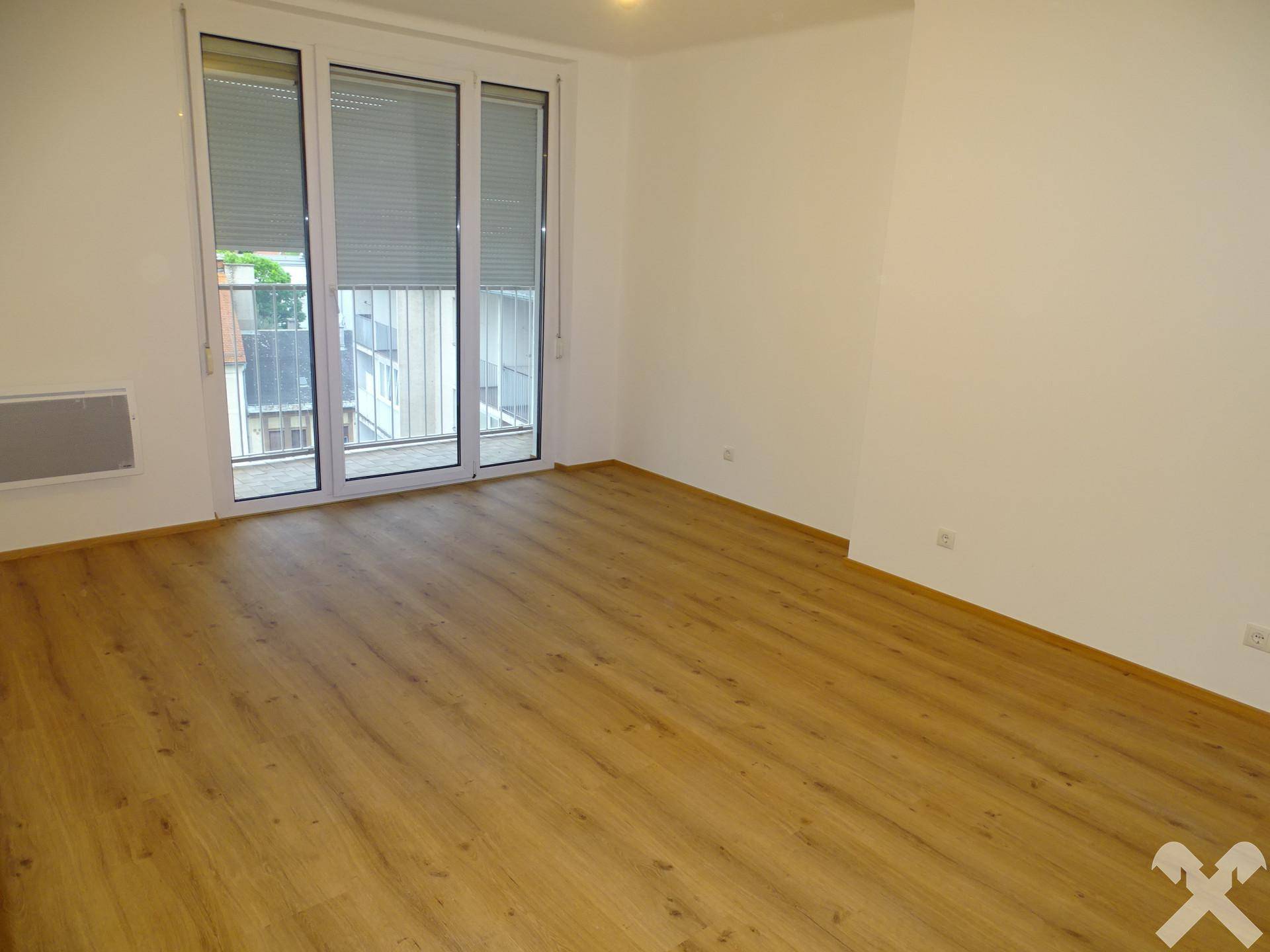 Geräumiges Zimmer mit Laminatboden und Zugang zu einem Balkon.