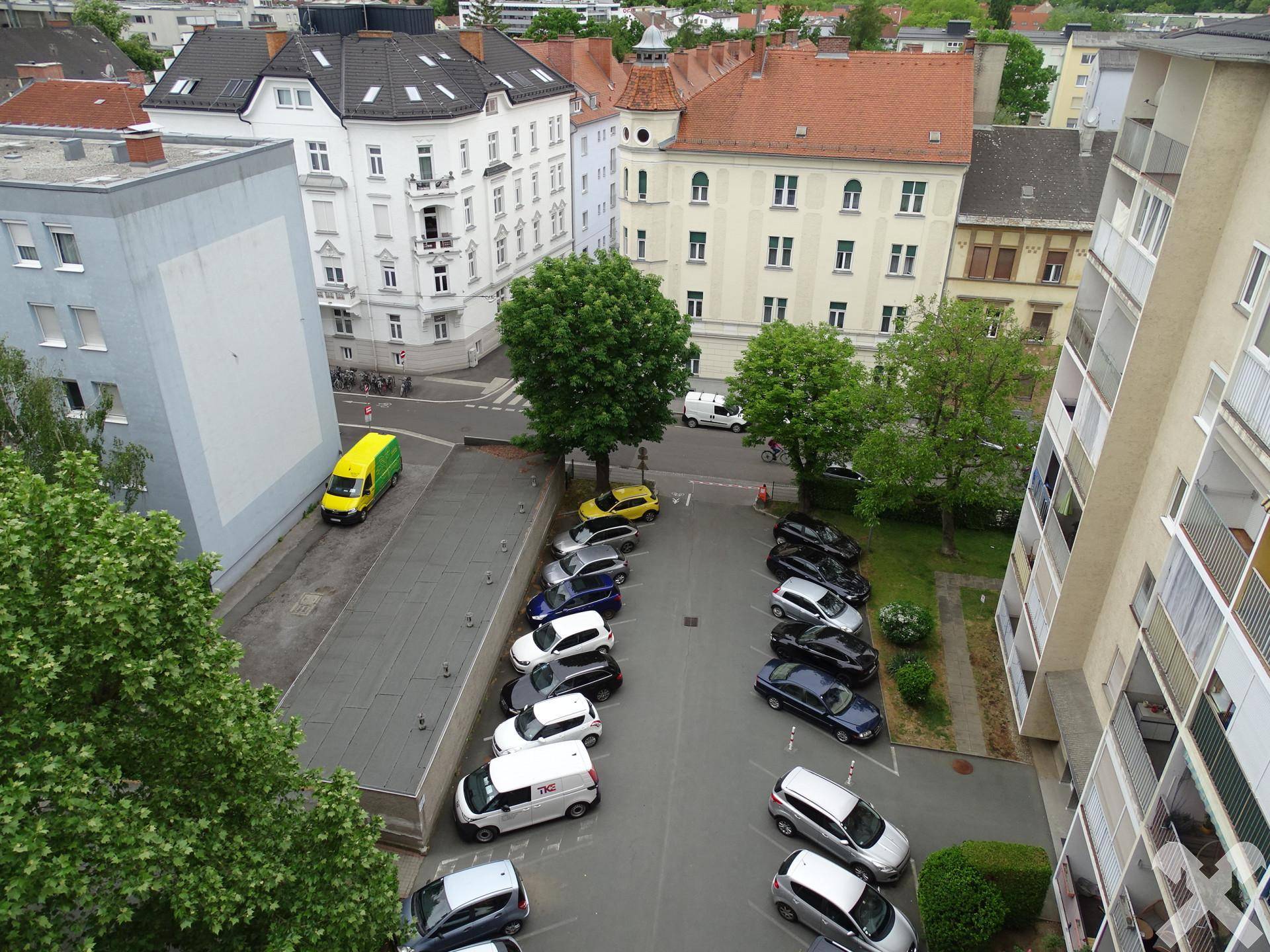 Blick von oben auf einen Parkplatz und die umliegenden Wohngebäude.