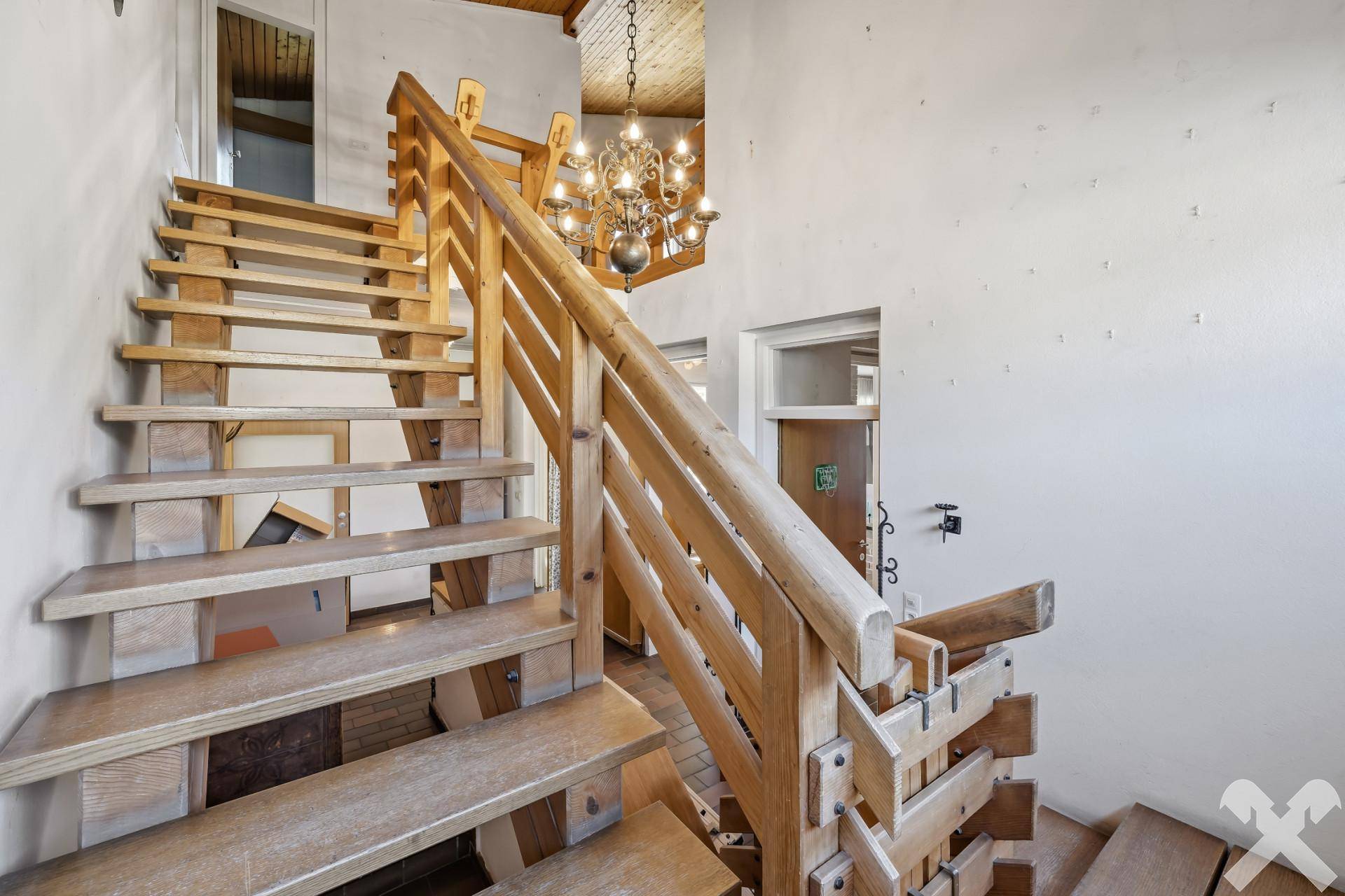 Holztreppe mit elegantem Kronleuchter, die die verschiedenen Ebenen des Hauses verbindet.
