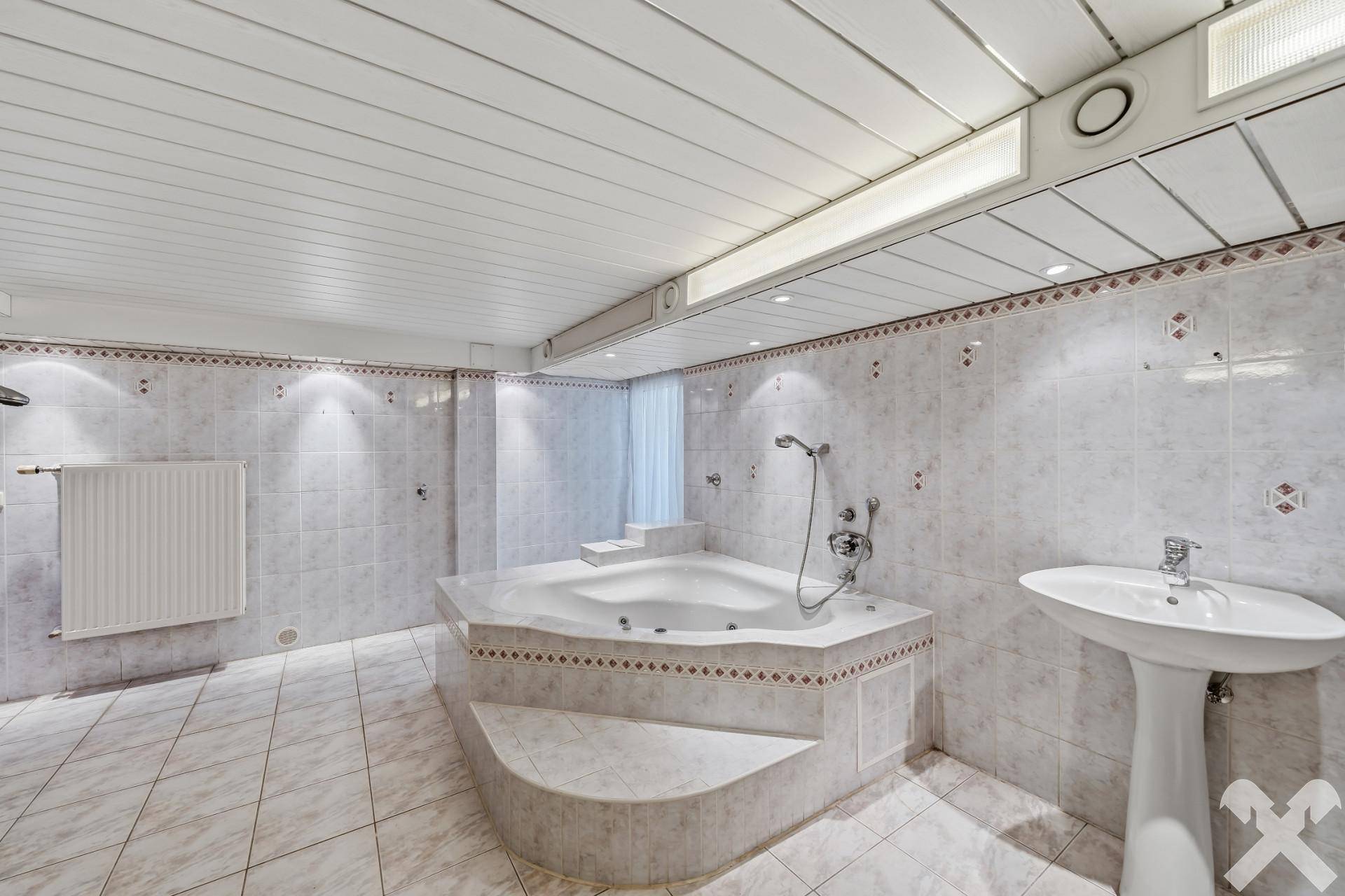 Geräumiges Badezimmer mit Eck-Whirlpool-Badewanne und hellen Fliesen.