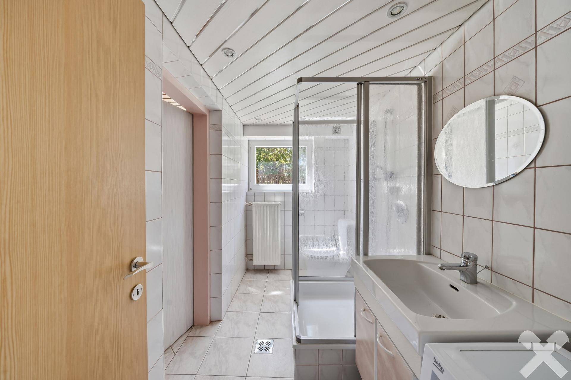 Modernes Badezimmer mit Dusche, Waschbecken und Fenster für Tageslicht.