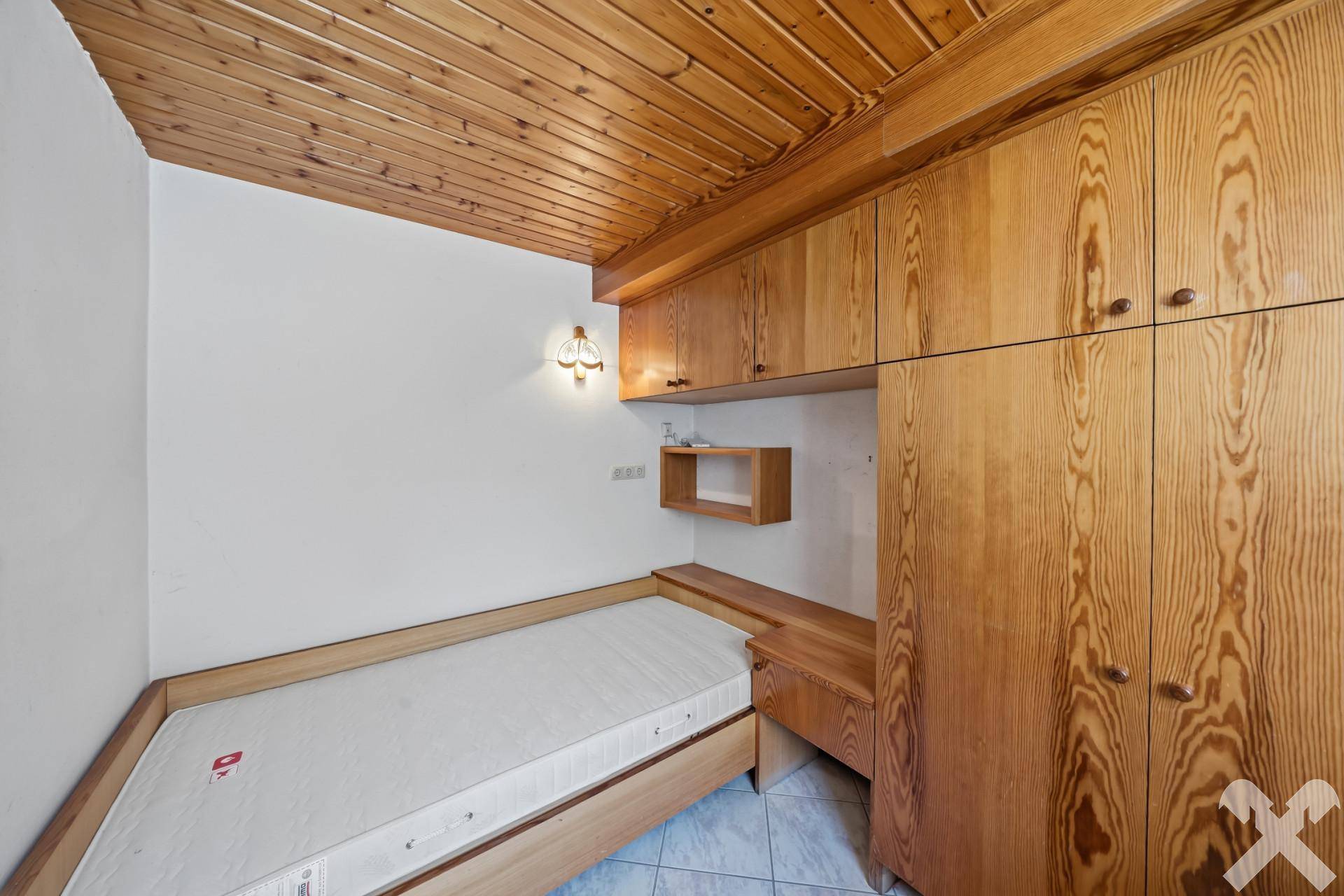 Gemütliches Schlafzimmer mit Holzbett, Einbauschränken und Holzdecke.