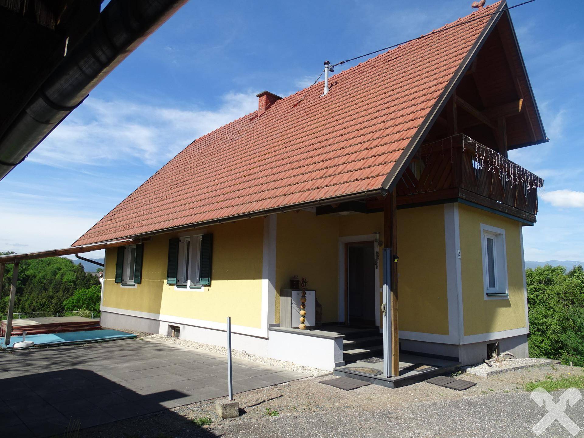 Ansicht des gelben Hauses mit Balkon und gepflastertem Bereich im Freien.