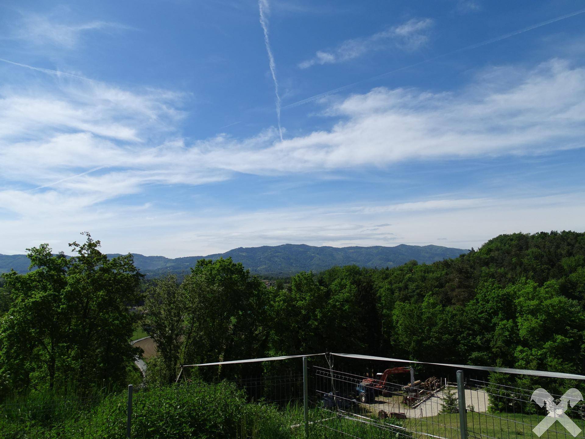 Panoramablick auf die bewaldete Hügellandschaft und den blauen Himmel.