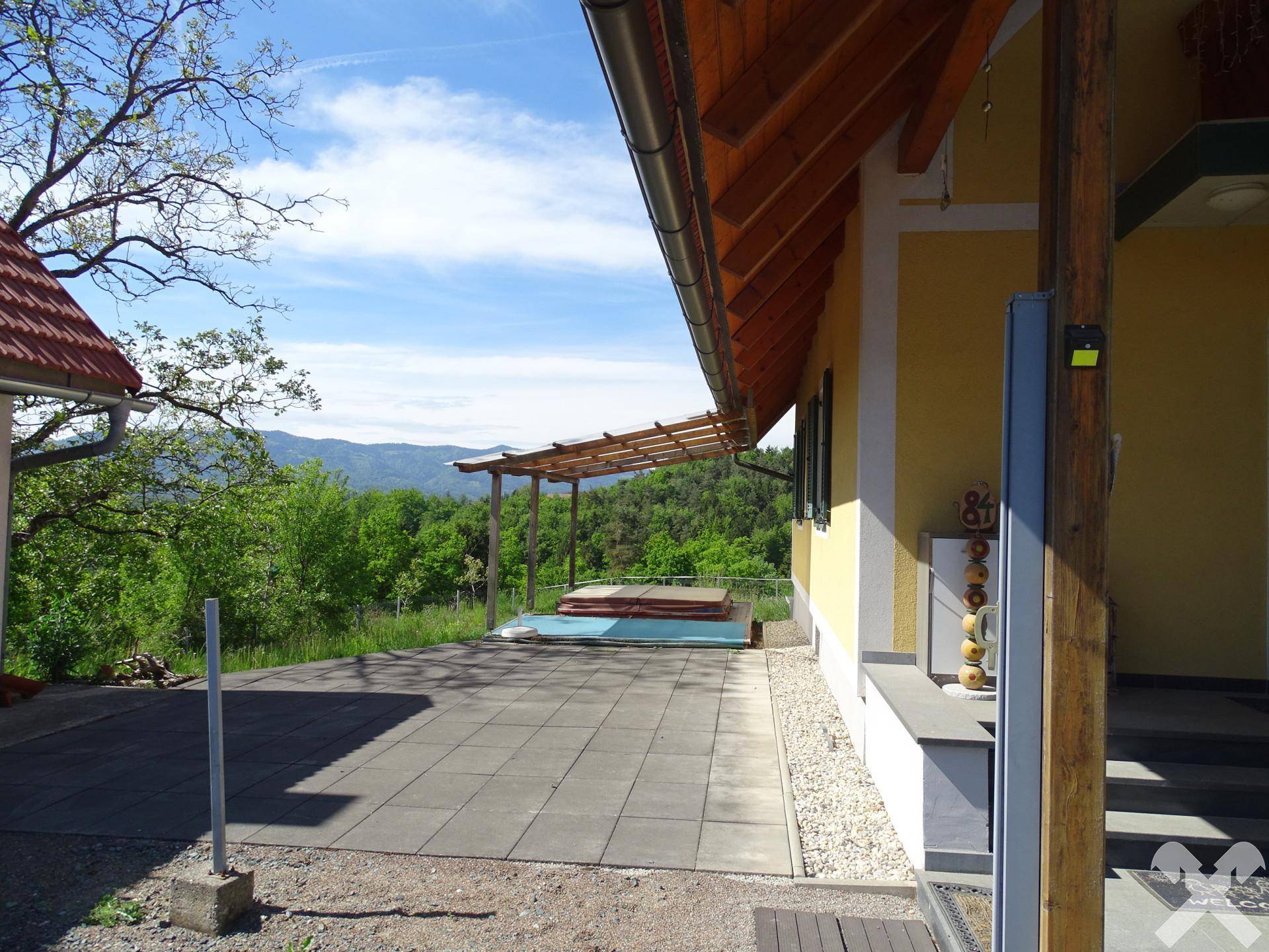 Große gepflasterte Terrasse mit Überdachung und kleinem Pool oder Whirlpool.