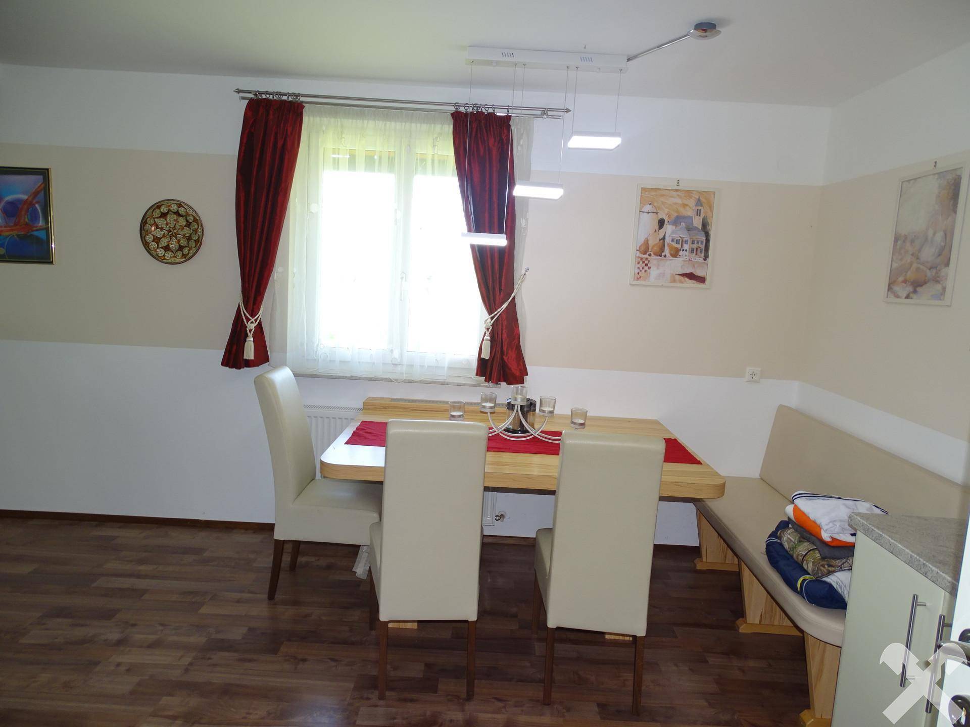 Gemütlicher Essbereich mit Holztisch, Eckbank und dunklem Laminatboden.