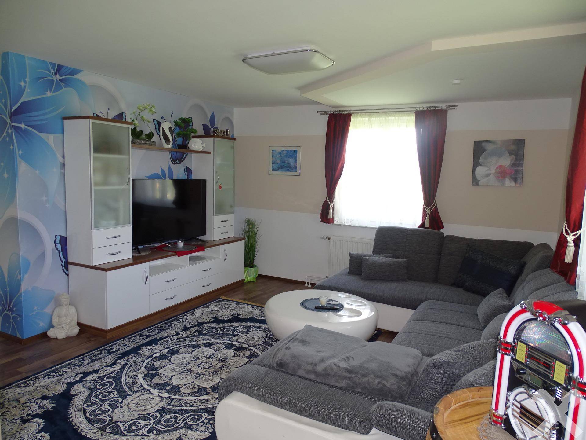 Geräumiges Wohnzimmer mit großem Ecksofa, Medieneinheit und dekorativer Wandtapete.