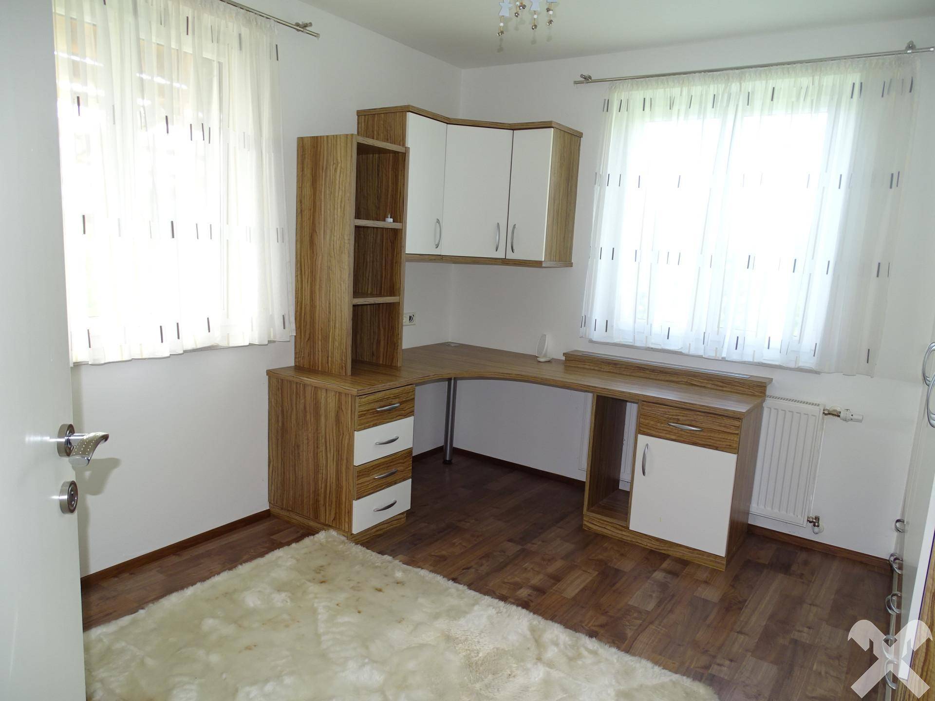 Helles Arbeitszimmer mit Schreibtisch, Regalen und Laminatboden.