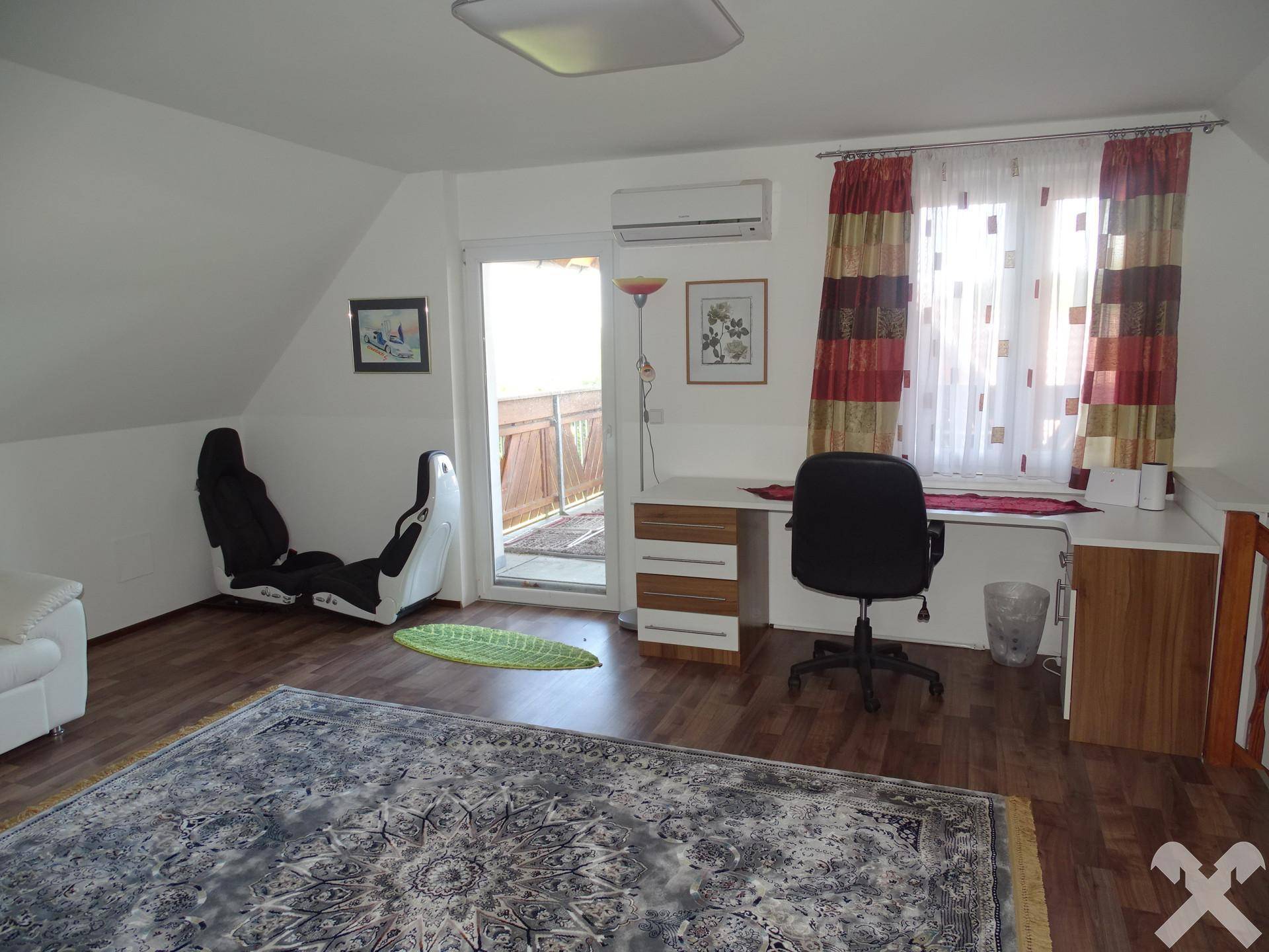 Dachboden-Arbeitsbereich mit Schreibtisch, Klimaanlage und Zugang zum Balkon.