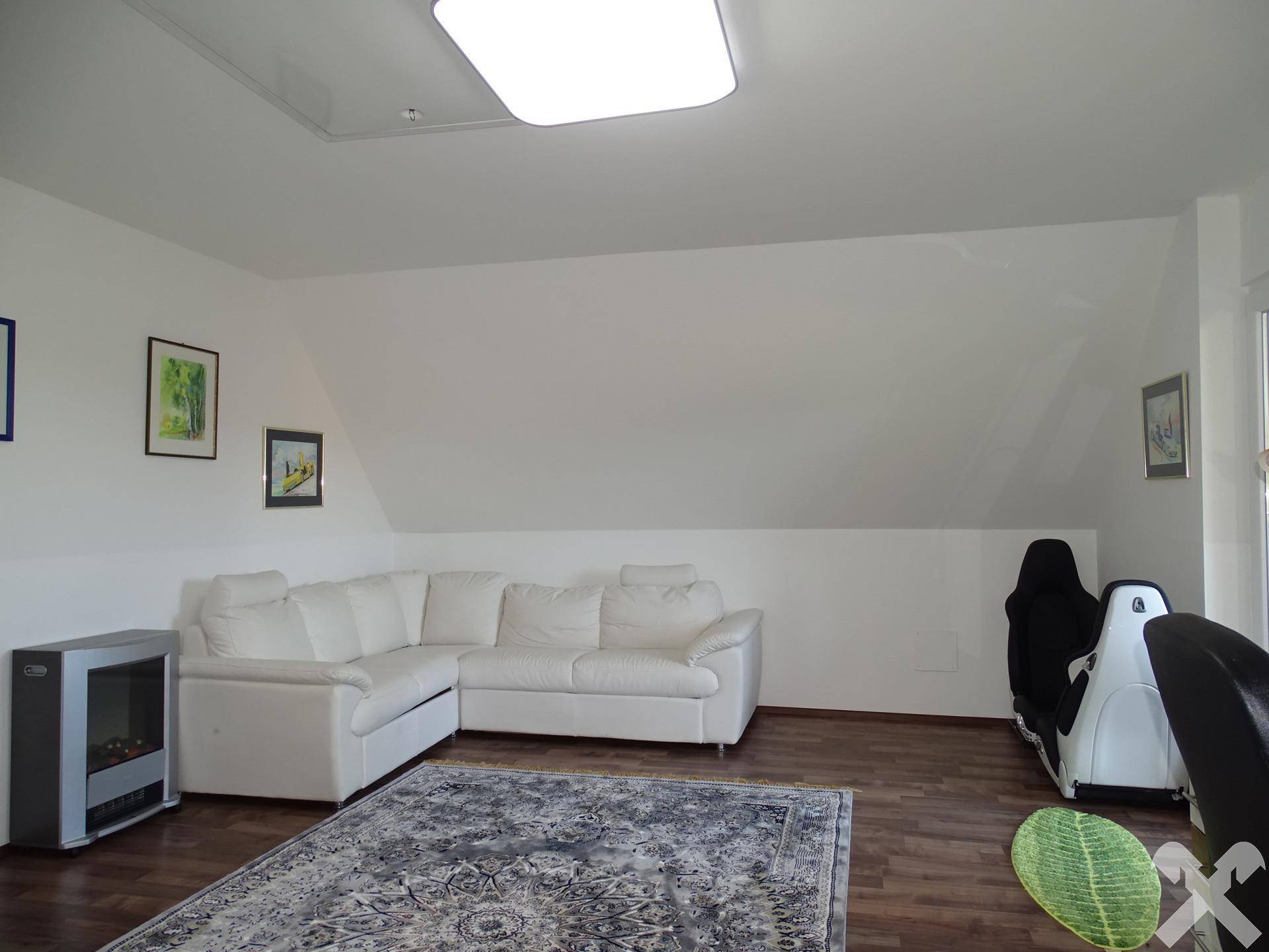Heller Dachboden-Wohnbereich mit weißem Sofa und Teppich.