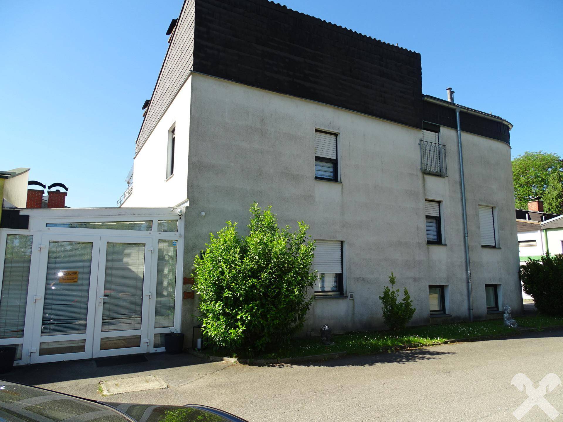 Seitenansicht des Gebäudes mit einem modernen Wintergarten und Rollläden an den Fenstern.